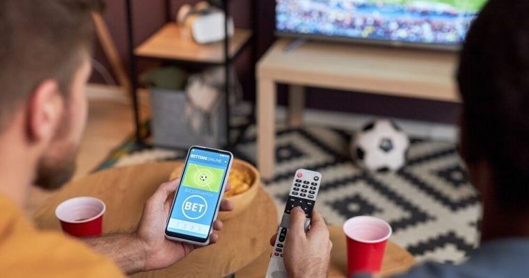 Two men watching football match and placing online sports bets