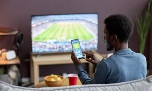 man betting on a sports betting app while watching football match