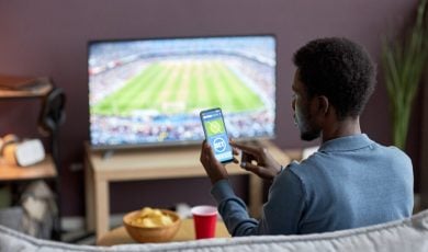 man betting on a sports betting app while watching football match