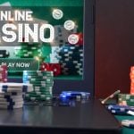 Concept of playing online casino games with laptop with gaming application on plush green mat and stacks of chips on top and around. Front view.