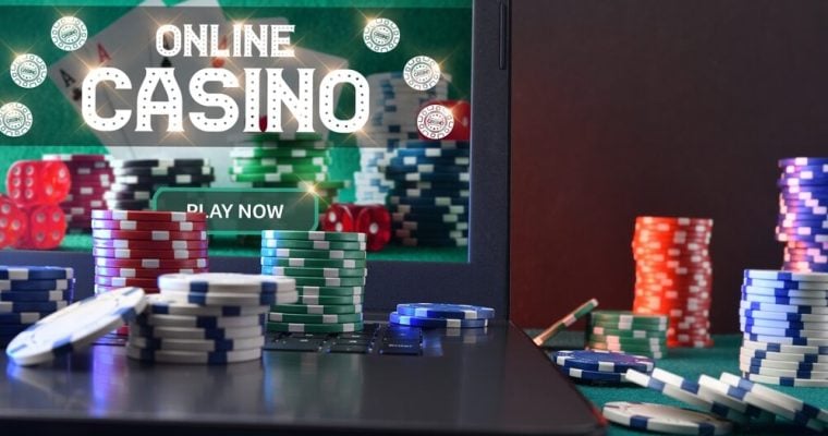 Concept of playing online casino games with laptop with gaming application on plush green mat and stacks of chips on top and around. Front view.