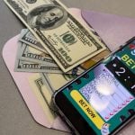 smartphone with sports bet application on dollar bills