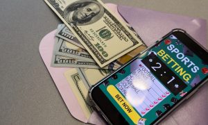 smartphone with sports bet application on dollar bills