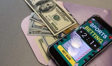 smartphone with sports bet application on dollar bills
