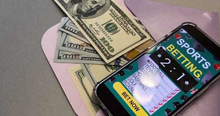 smartphone with sports bet application on dollar bills