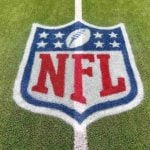 An NFL logo on a green artificial grass football field line