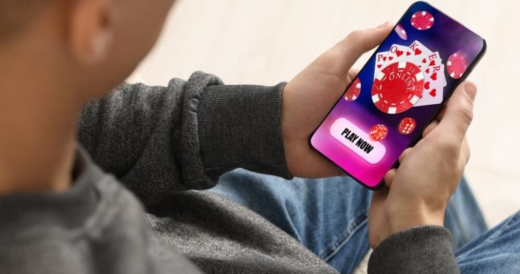 Man playing online poker on mobile phone indoors