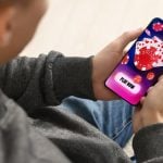 Man playing online poker on mobile phone indoors
