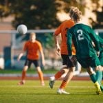 Soccer football players kick a ball towards a goal during a match in the soccer stadium