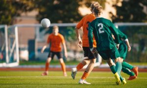 Soccer football players kick a ball towards a goal during a match in the soccer stadium