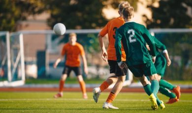 Soccer football players kick a ball towards a goal during a match in the soccer stadium