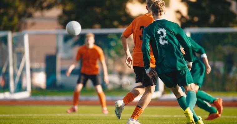 Soccer football players kick a ball towards a goal during a match in the soccer stadium
