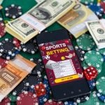 Sports Betting on a smartphone surrounded by poker chips and US dollars