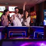 Three cheerful friends enjoy a fun time at a vibrant casino arcade