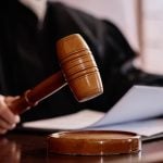 Wooden gavel held by experienced female judge over sounding block