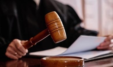 Wooden gavel held by experienced female judge over sounding block