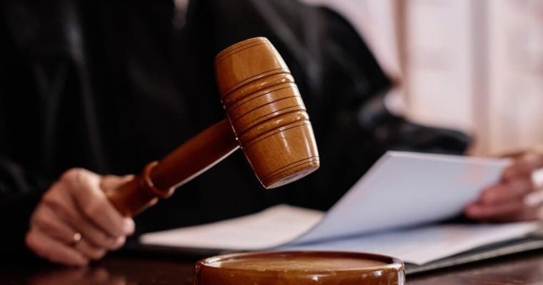 Wooden gavel held by experienced female judge over sounding block