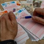 man crosses out 6 digits on a ticket with a pen, lucky numbers and a big cash win in the lottery