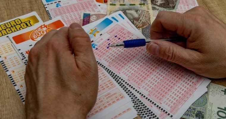 man crosses out 6 digits on a ticket with a pen, lucky numbers and a big cash win in the lottery