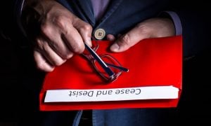 A man opens a letter with cease and desist