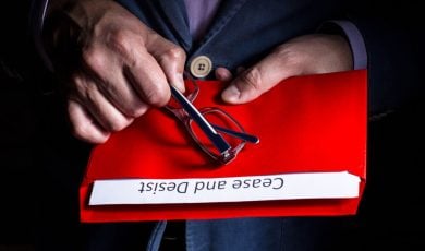 A man opens a letter with cease and desist
