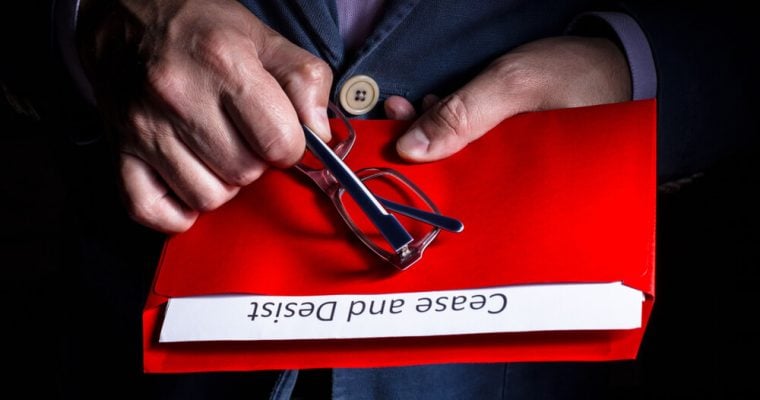 A man opens a letter with cease and desist