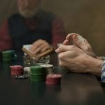 An intense poker game highlighted by chips, cards and players in a mysterious atmosphere