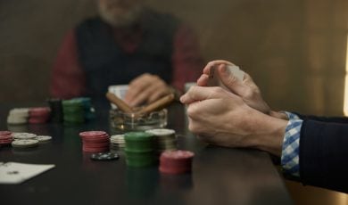 An intense poker game highlighted by chips, cards and players in a mysterious atmosphere