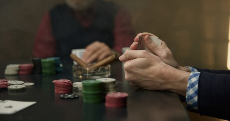 An intense poker game highlighted by chips, cards and players in a mysterious atmosphere