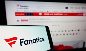 Cellphone with logo of US online sportswear retailer Fanatics Inc on screen in front of website