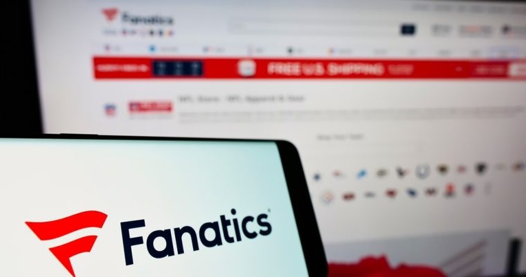 Cellphone with logo of US online sportswear retailer Fanatics Inc on screen in front of website