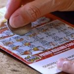 Close up of a person using a coin to scratch off a lottery ticket for a chance at a prize