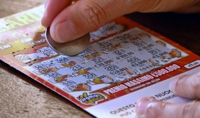 Close up of a person using a coin to scratch off a lottery ticket for a chance at a prize