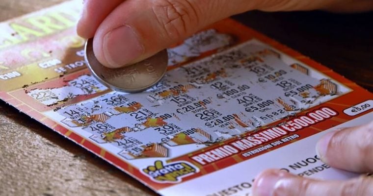 Close up of a person using a coin to scratch off a lottery ticket for a chance at a prize