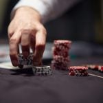 Dealer or croupier shuffles poker cards in a casino on the background of a table, chips
