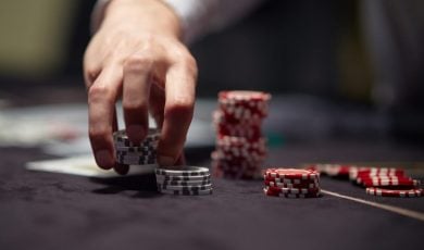 Dealer or croupier shuffles poker cards in a casino on the background of a table, chips