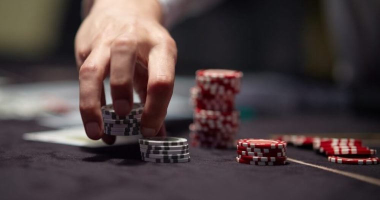 Dealer or croupier shuffles poker cards in a casino on the background of a table, chips