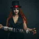 Girl in a top hat with playing cards on a dark background
