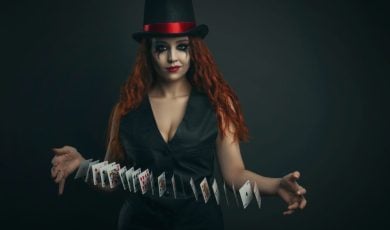 Girl in a top hat with playing cards on a dark background