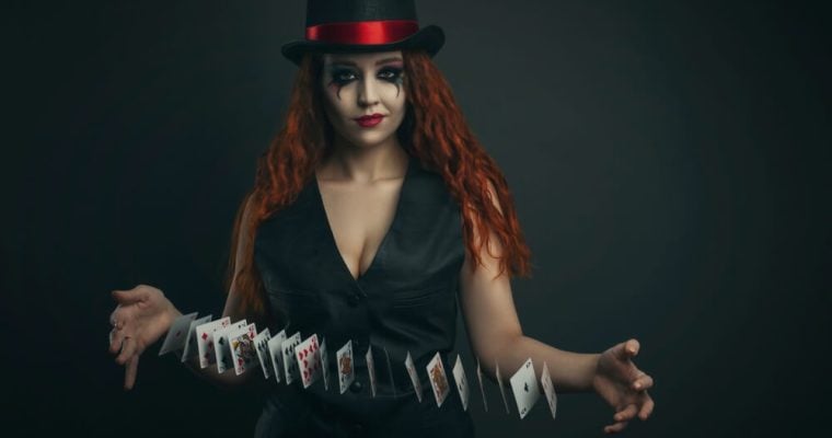 Girl in a top hat with playing cards on a dark background