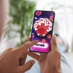 Man playing online poker on mobile phone at home, closeup