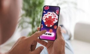 Man playing online poker on mobile phone at home, closeup