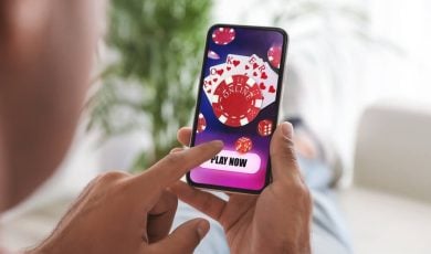 Man playing online poker on mobile phone at home, closeup