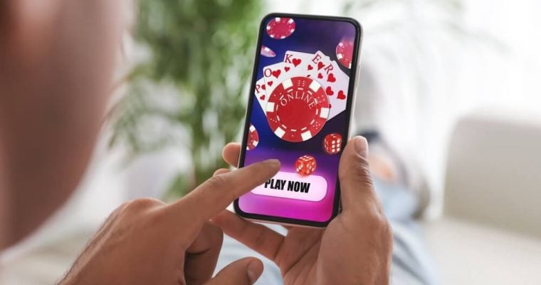 Man playing online poker on mobile phone at home, closeup