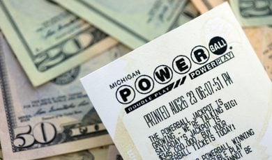 Power Ball lottery ticket lies on many dollar bills close up