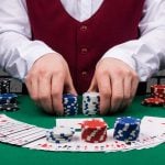 dealer's hands holding stacks of poker chips and cards
