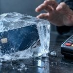 A person reaches toward a payment terminal next to a debit card encased in a block of ice.